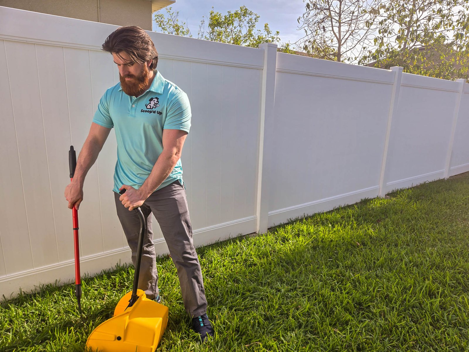 Scoopd Up employee scooping dog poop in yard