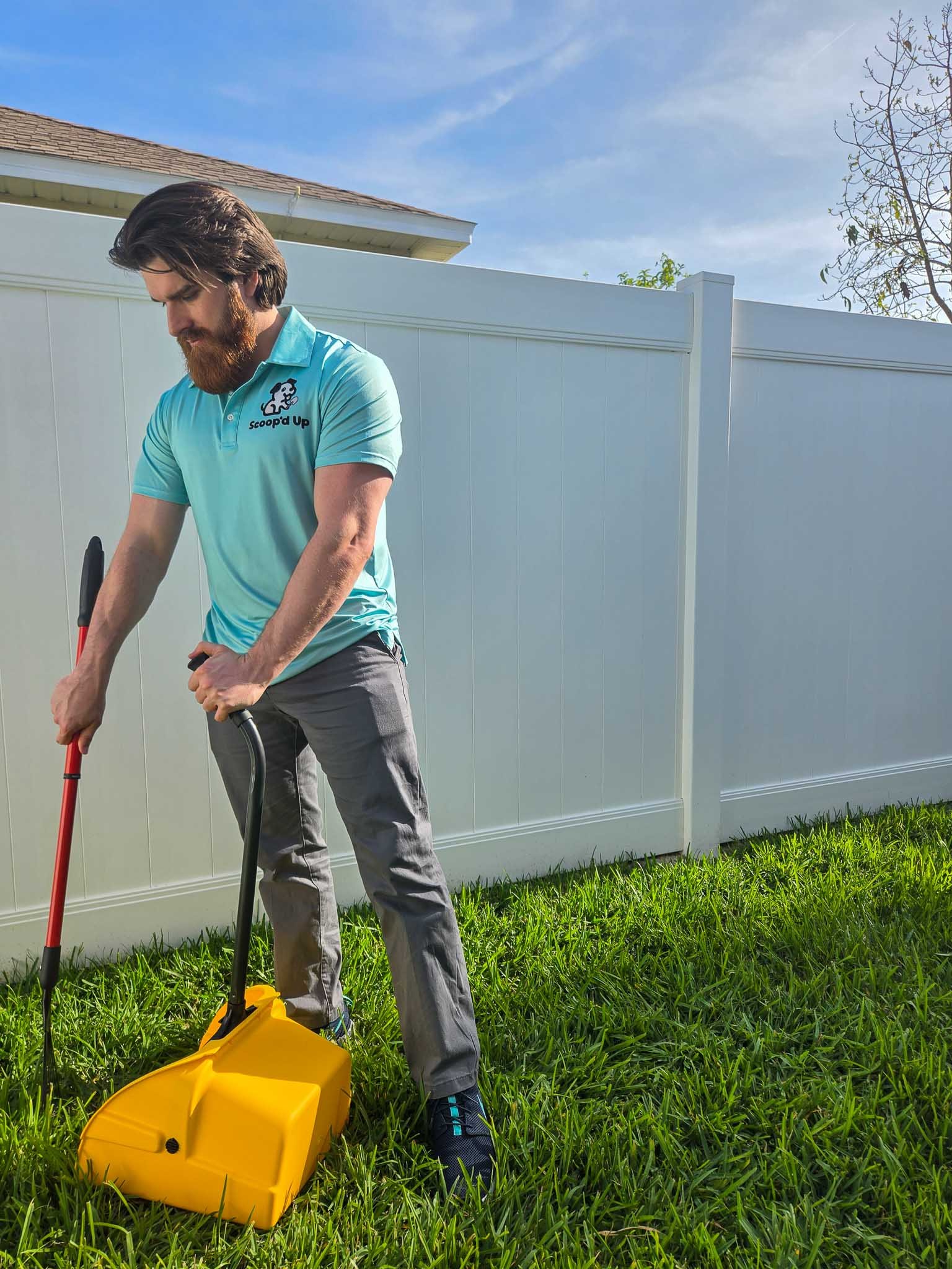 Scoopd Up employee scooping dog poop in yard vertical